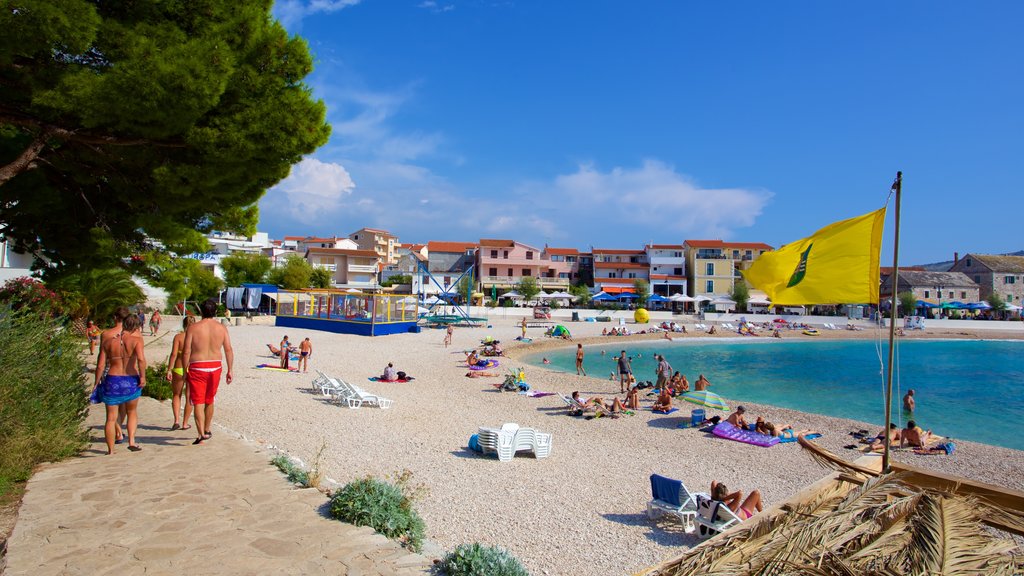 Spiaggia di Primosten che include spiaggia di ciottoli cosi come un piccolo gruppo di persone