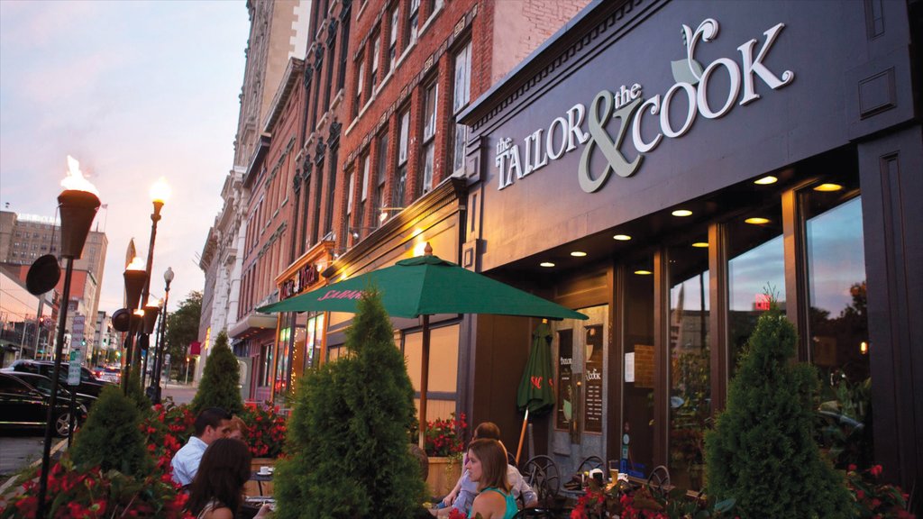 Utica showing signage and outdoor eating as well as a small group of people