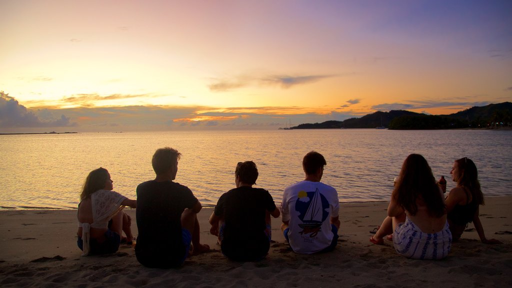 Musket Cove caracterizando uma praia e um pôr do sol assim como um pequeno grupo de pessoas