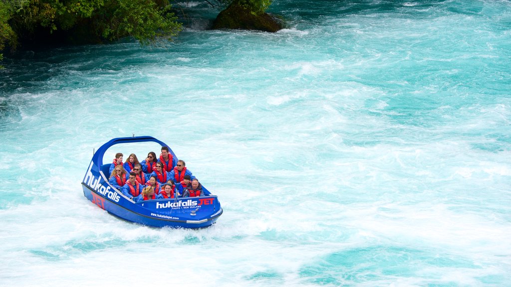 Cascade de Huka montrant une rivière ou un ruisseau et bateau aussi bien que un petit groupe de personnes