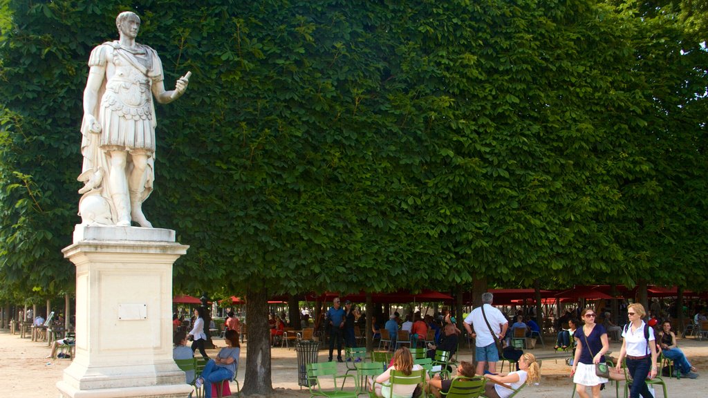 Jardin des Tuileries que inclui uma estátua ou escultura e um jardim assim como um pequeno grupo de pessoas