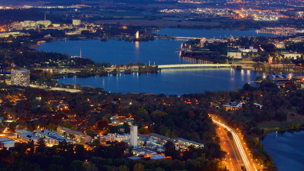 Telstra Tower which includes a city, night scenes and a lake or waterhole