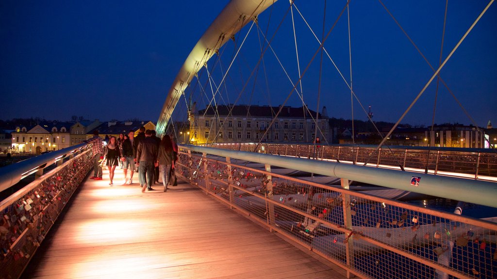 Father Bernatka Footbridge which includes night scenes and a bridge as well as a small group of people