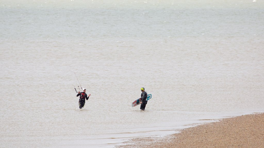 Whitstable Beach mostrando uma praia de pedras assim como um pequeno grupo de pessoas