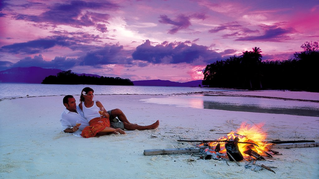 Islas Salomón que incluye una puesta de sol y una playa de arena y también una pareja