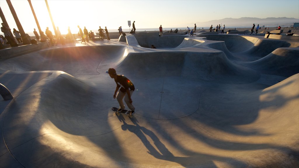 Venice Beach mostrando um parquinho e um pôr do sol assim como um homem sozinho