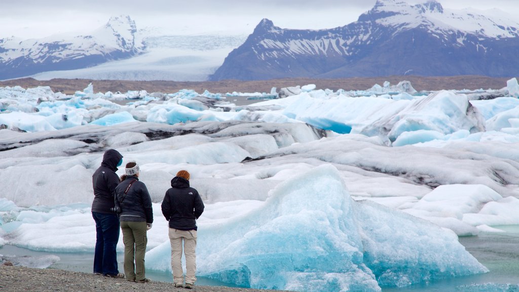 Lagoa Jökulsárlón caracterizando neve assim como um pequeno grupo de pessoas