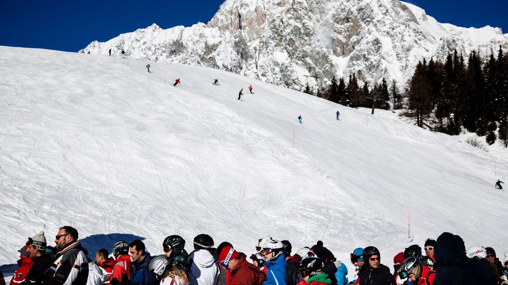 Courmayeur ofreciendo nieve y montañas y también un gran grupo de personas