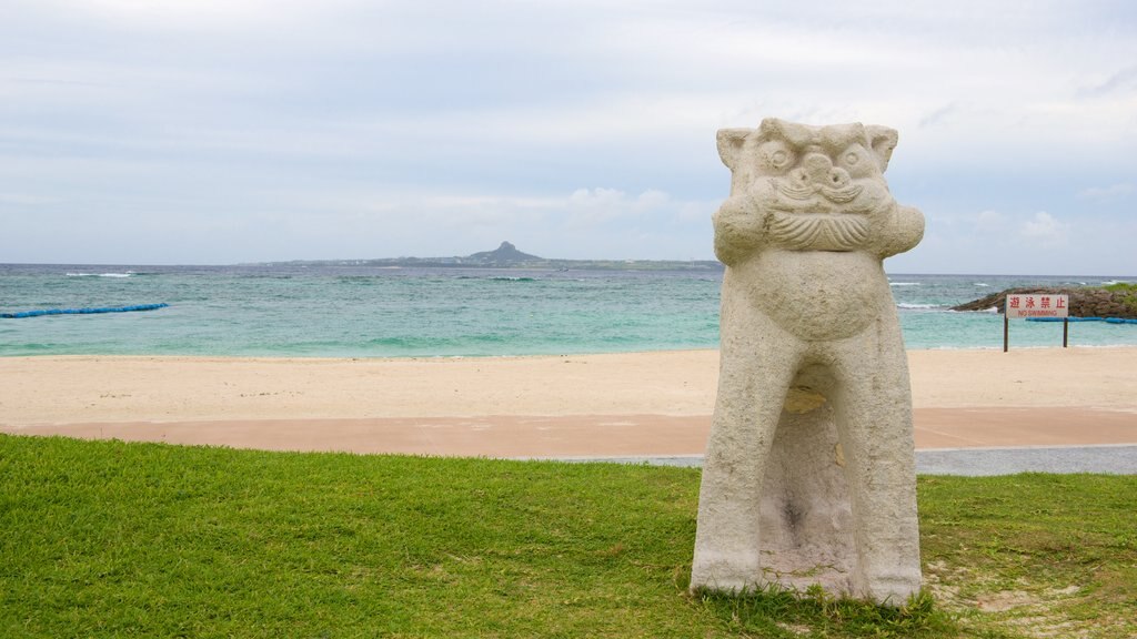 Okinawa ofreciendo una estatua o escultura, una playa de arena y una ciudad costera