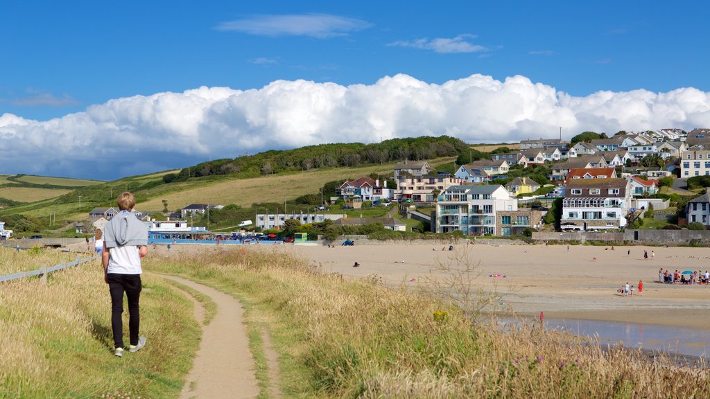 Porth Beach featuring a coastal town and a sandy beach as well as an individual male