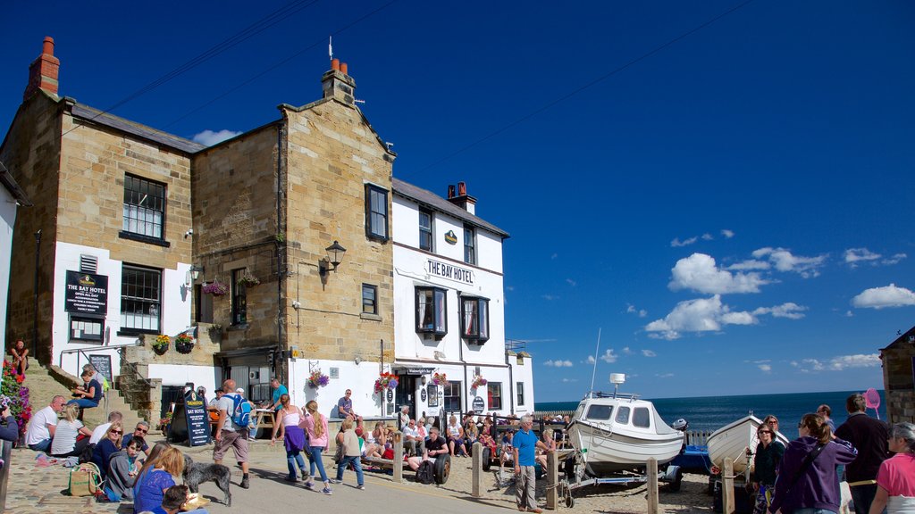 Robin Hood\'s Bay Beach featuring a coastal town and heritage architecture as well as a large group of people