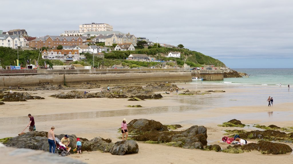 Newquay showing a sandy beach and a coastal town as well as a large group of people