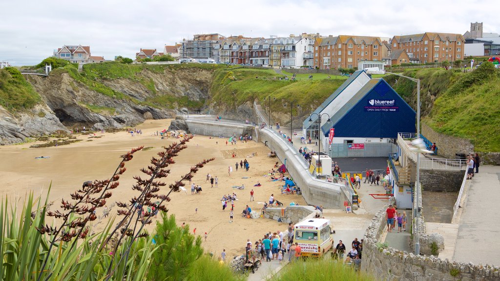 Newquay ofreciendo una playa de arena y una ciudad costera y también un gran grupo de personas