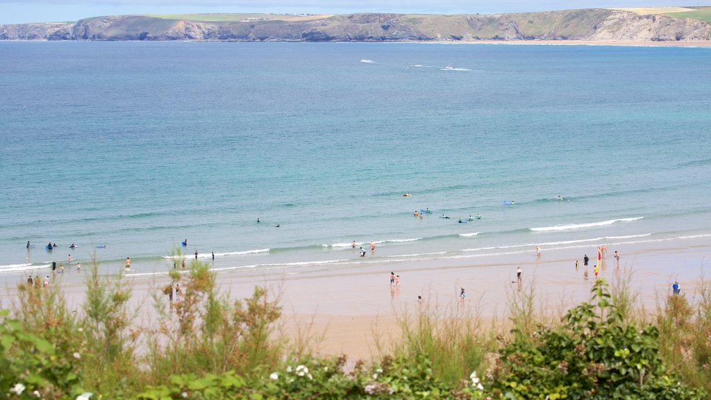 Newquay mettant en vedette baignade et plage de sable aussi bien que important groupe de personnes