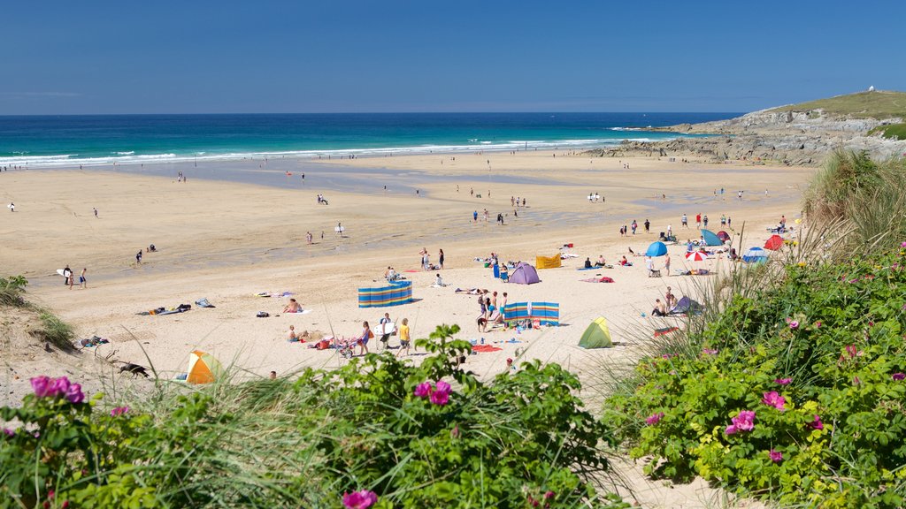 Fistral Beach showing a sandy beach and rocky coastline as well as a large group of people