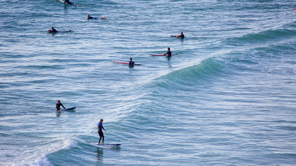 Watergate Bay featuring surfing and waves as well as a small group of people