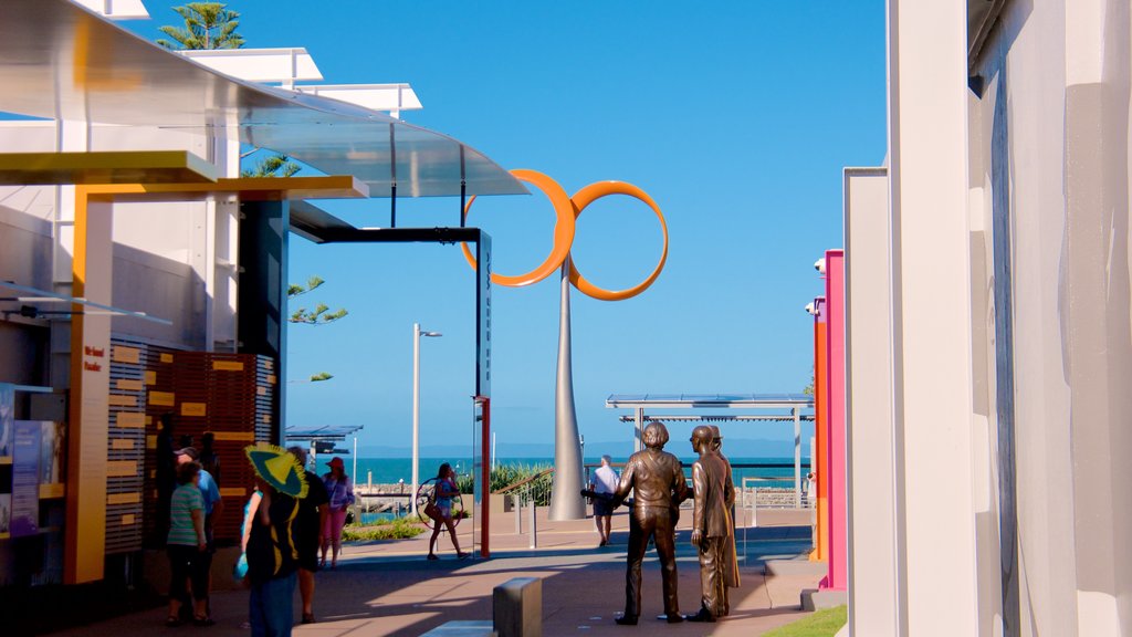 Bee Gees Way featuring general coastal views and outdoor art as well as a small group of people