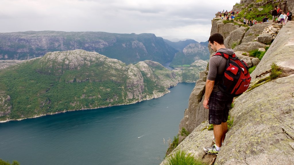 Preikestolen showing mountains and a lake or waterhole as well as an individual male