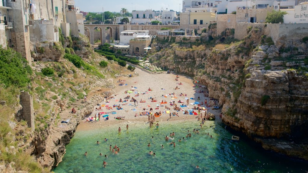 Polignano a Mare caracterizando uma praia e litoral rochoso assim como um grande grupo de pessoas