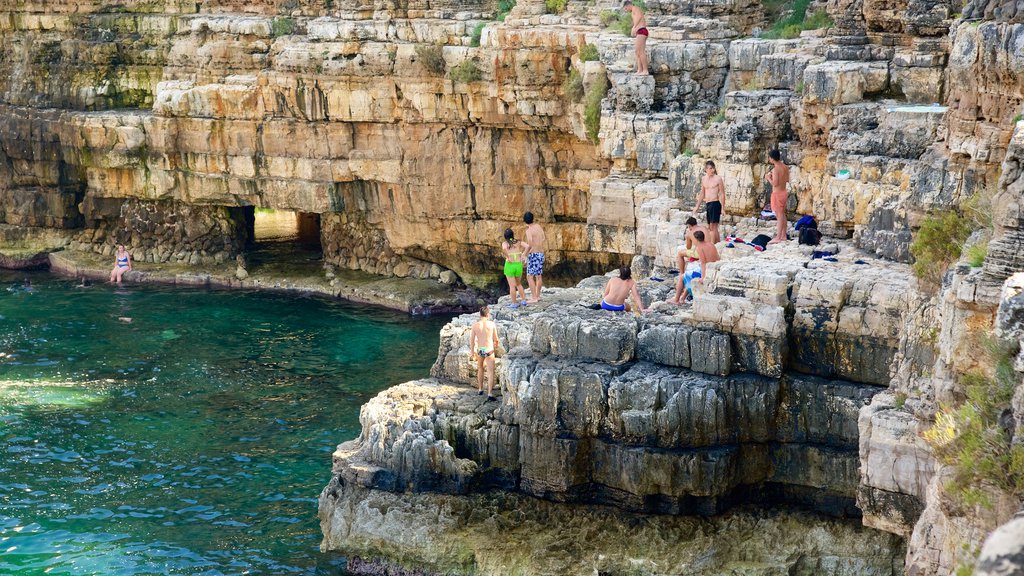 Polignano a Mare showing rocky coastline as well as a large group of people