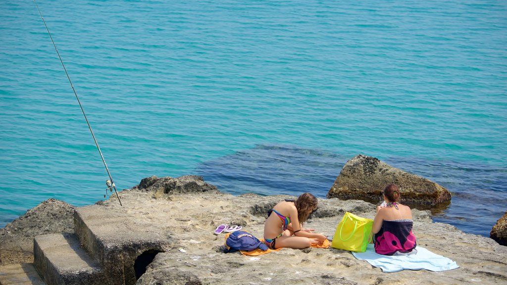 Zona portuária de Otranto caracterizando litoral rochoso assim como um pequeno grupo de pessoas