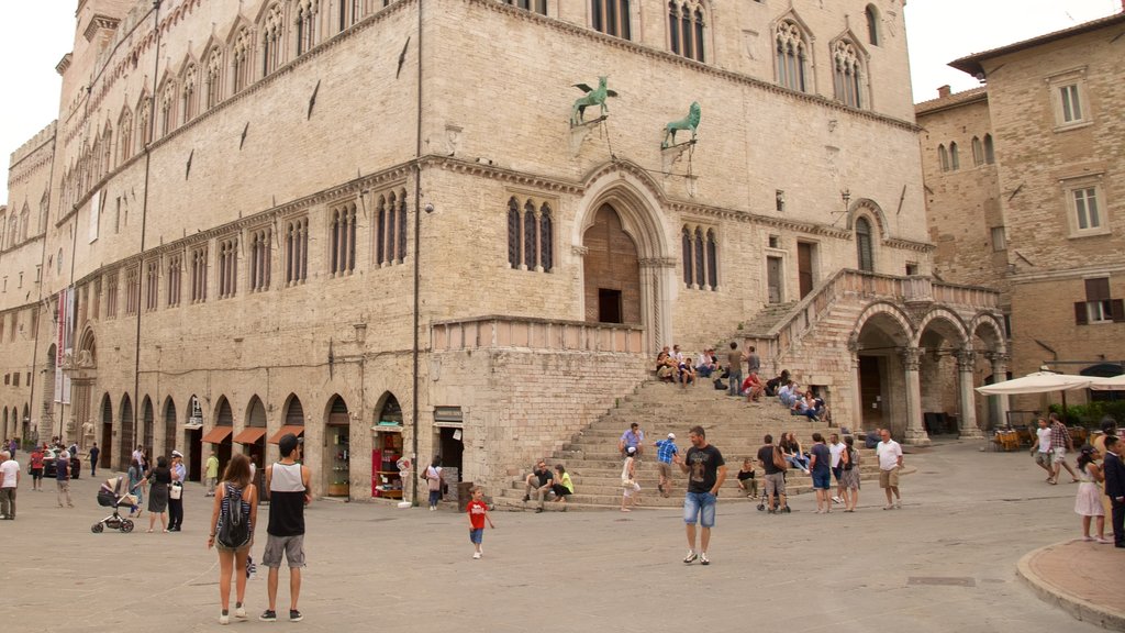 Palazzo dei Priori showing a square or plaza and heritage architecture as well as a large group of people