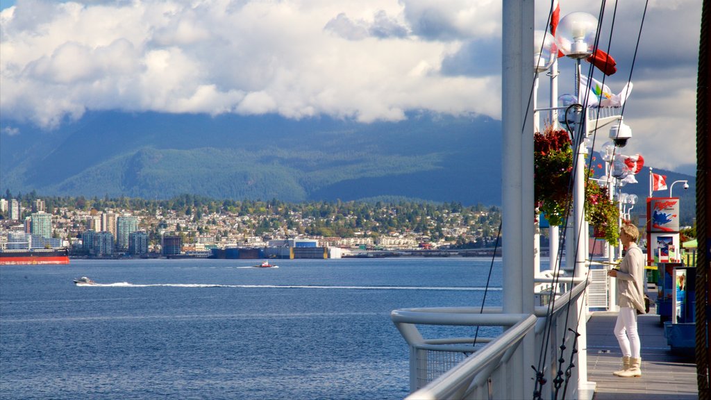 Canada Place showing a city and a bay or harbour as well as an individual female