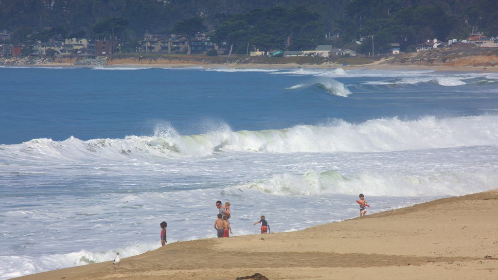 Half Moon Bay ofreciendo vista general a la costa y una playa de arena y también una familia