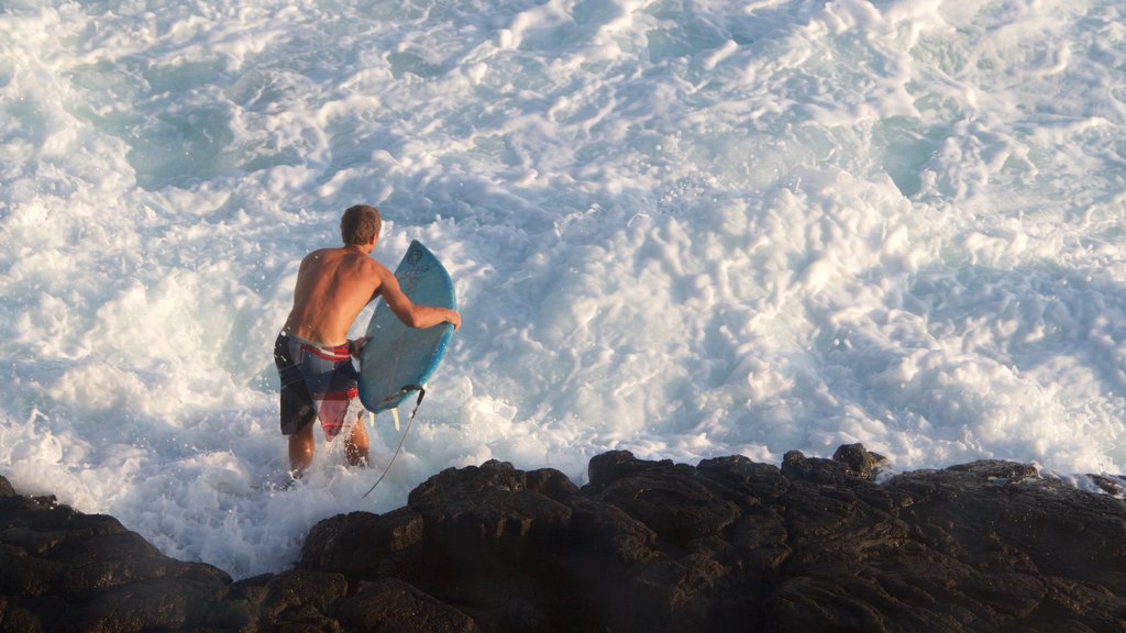 Kailua-Kona featuring surfing and rocky coastline as well as an individual male