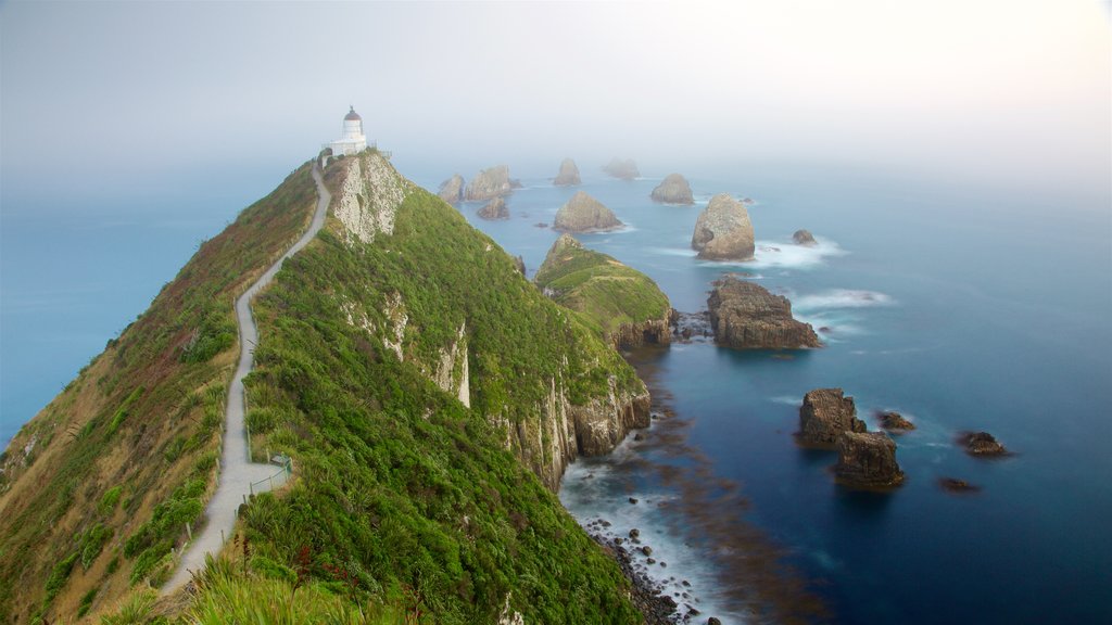 Kaka Point mostrando costa escarpada, neblina o niebla y un faro