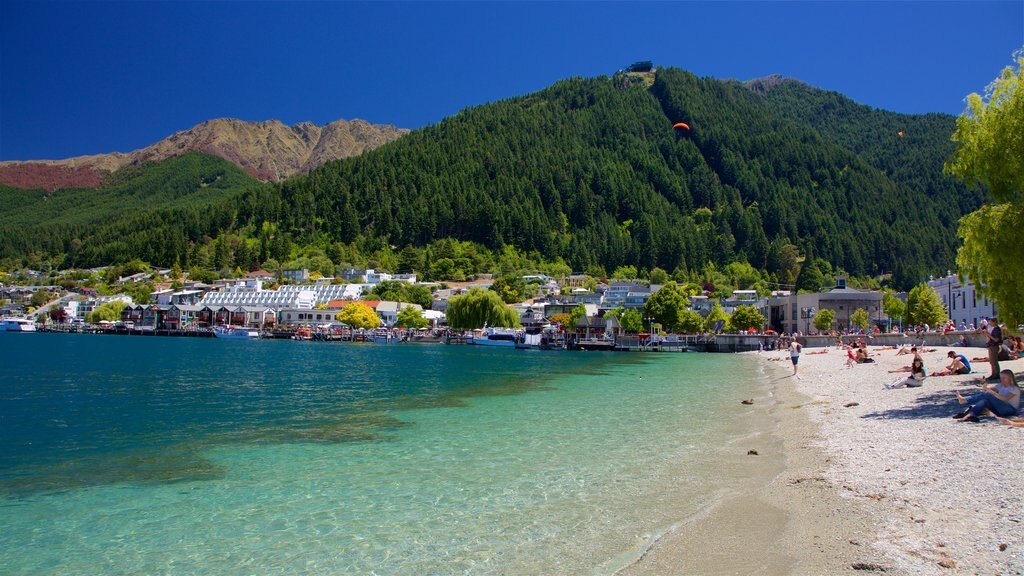 Playa de Queenstown mostrando una playa de piedras, una pequeña ciudad o aldea y un lago o espejo de agua