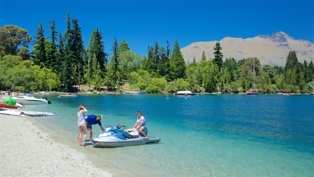 Playa de Queenstown que incluye jet ski, montañas y una playa de guijarros