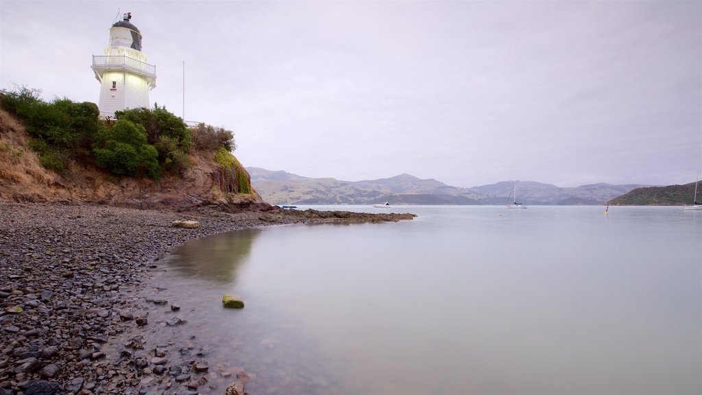 Akaroa mostrando uma praia de pedras, uma baía ou porto e um farol