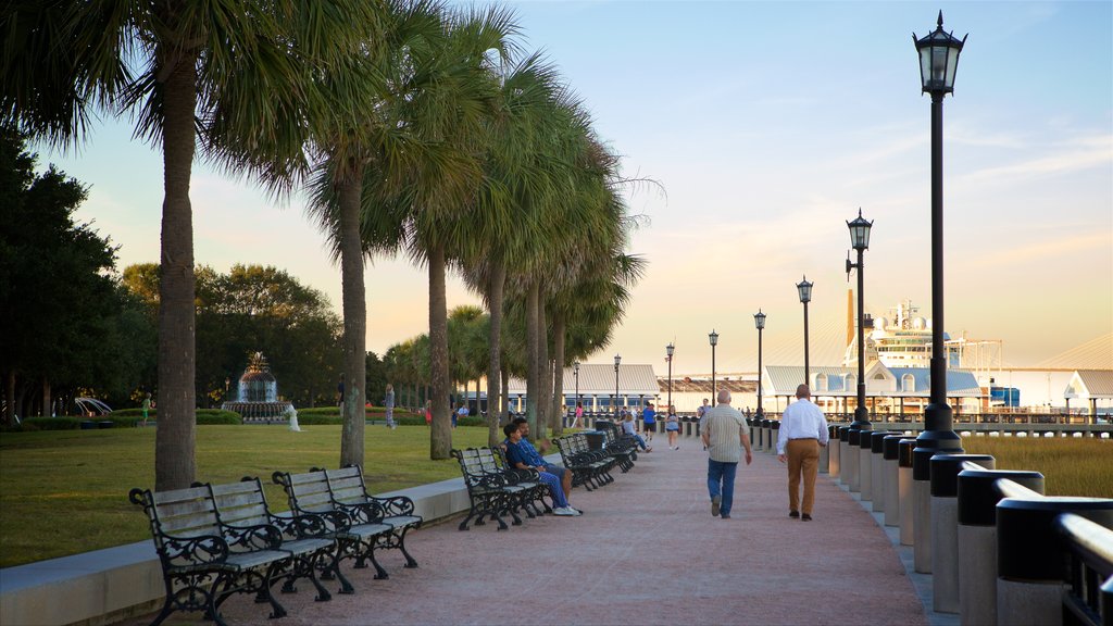 Charleston Waterfront Park mostrando un atardecer y jardín y también un pequeño grupo de personas