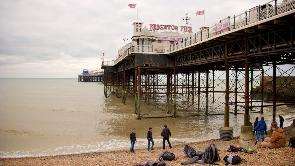 Brighton Pier som viser udsigt over kystområde og en sandstrand såvel som en lille gruppe mennesker