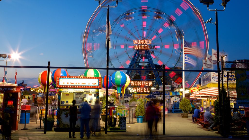 Coney Island featuring rides and night scenes as well as a small group of people