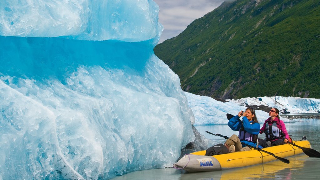 Valdez som visar kajak eller kanot och berg såväl som en liten grupp av människor