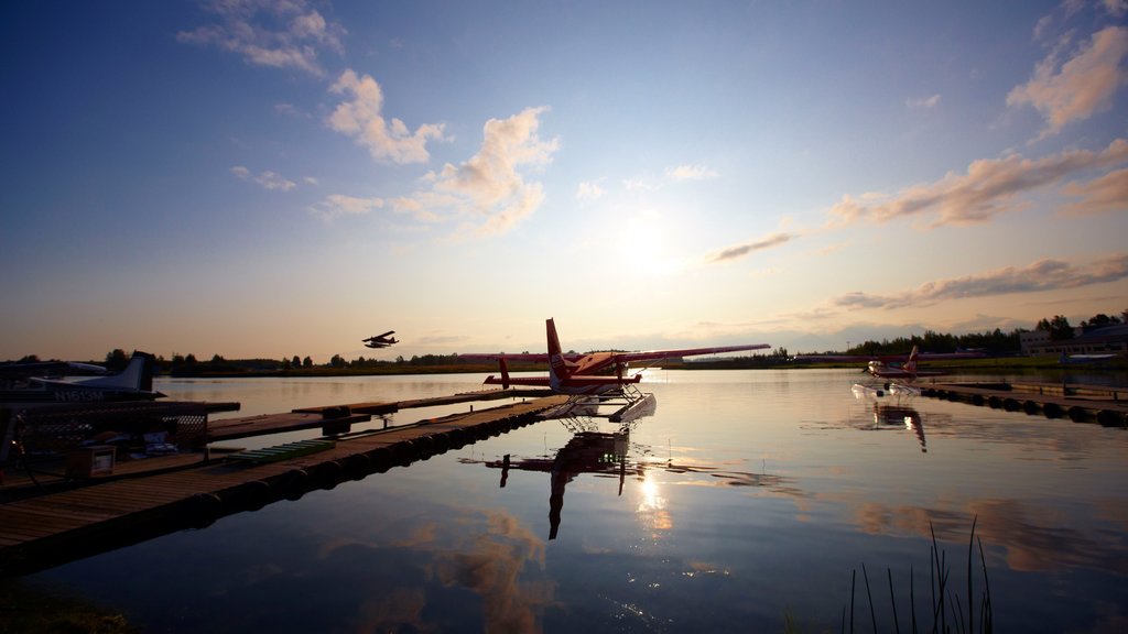 Kenai que incluye una bahía o puerto, una puesta de sol y aeronave