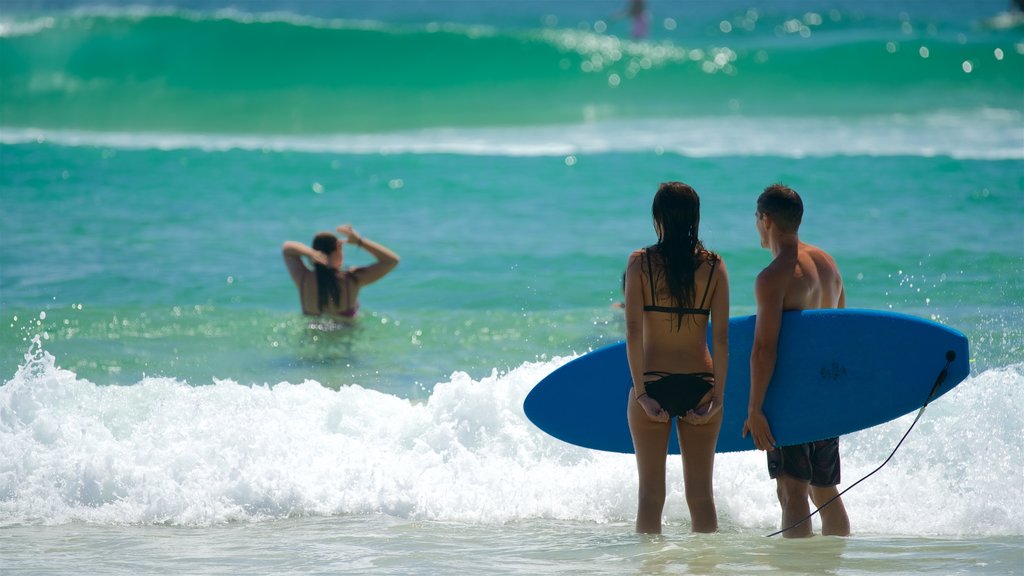 Wategos Beach showing surfing and a beach as well as a couple