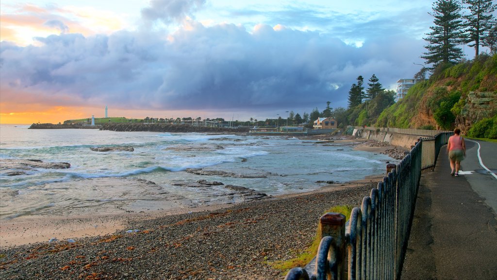 Wollongong Beach caracterizando uma praia de pedras, um pôr do sol e escalada ou caminhada