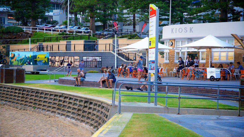 Wollongong Beach caracterizando jantar ao ar livre e uma praia de areia assim como um pequeno grupo de pessoas