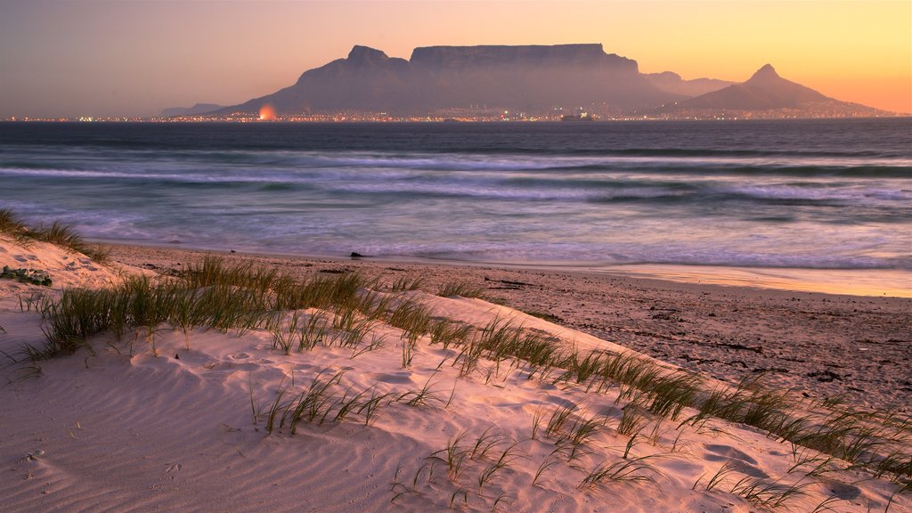 Bloubergstrand caracterizando montanhas, um pôr do sol e paisagens litorâneas