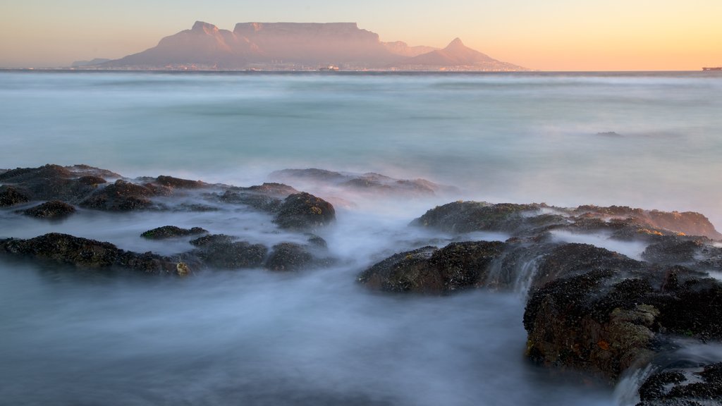 Bloubergstrand mostrando montañas, costa escarpada y una puesta de sol