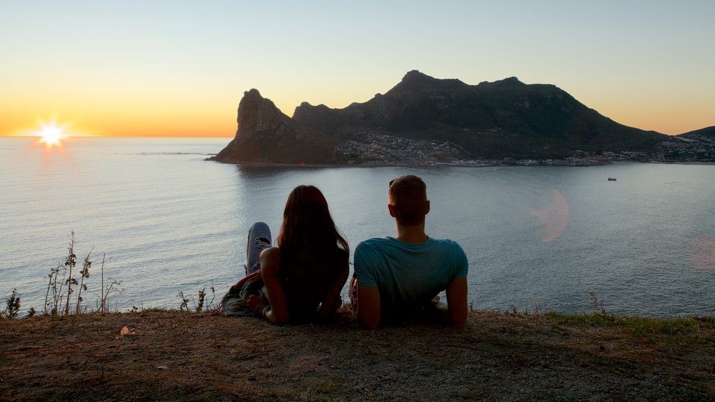 Chapmans Peak showing a sunset and rocky coastline as well as a couple