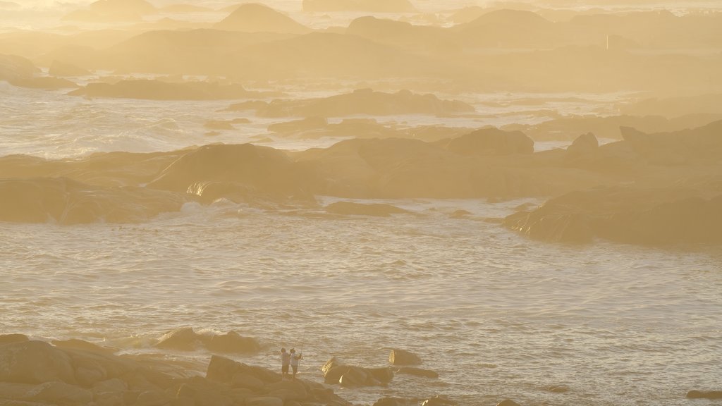 Leuchtturm von Cape Columbine das einen Sonnenuntergang und Felsküste sowie Paar