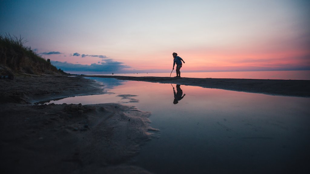 Grand Bend caracterizando paisagens litorâneas e um pôr do sol assim como uma criança sozinha