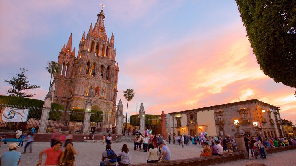 Parroquia de San Miguel Arcángel ofreciendo un atardecer, una plaza y arquitectura patrimonial