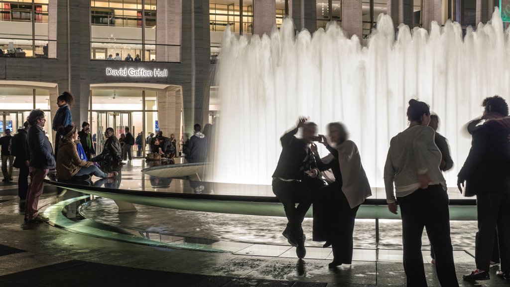 Lincoln Center for the Performing Arts featuring a fountain and night scenes as well as a small group of people