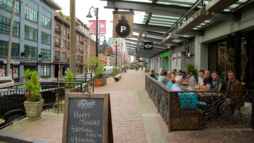 Yaletown featuring outdoor eating and signage as well as a small group of people