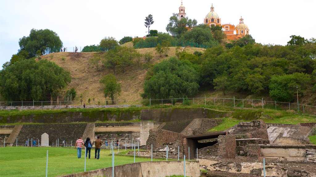 Great Pyramid of Cholula featuring building ruins and heritage elements as well as a small group of people